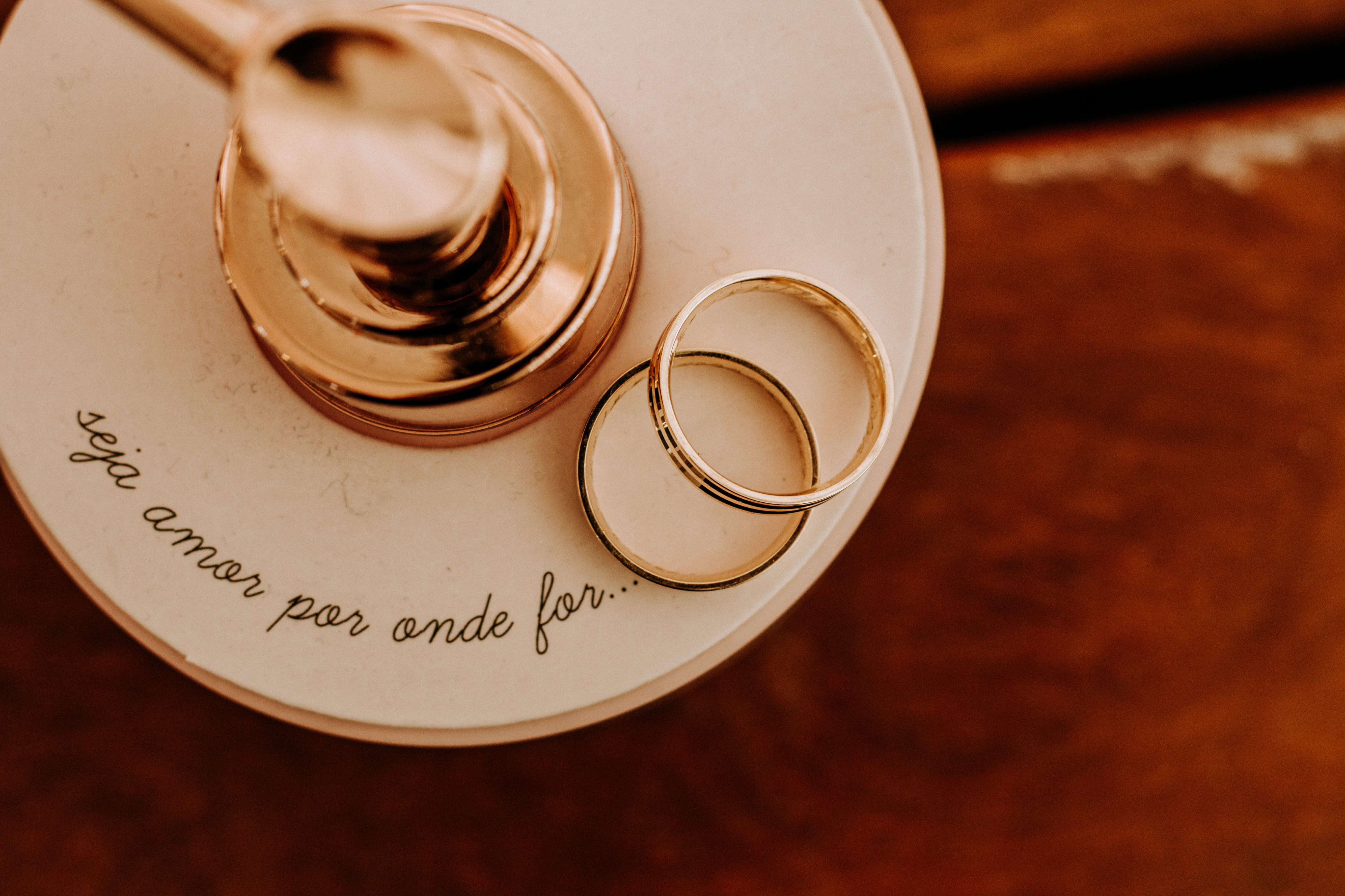 Mãos segurando alianças em cima de flores brancas